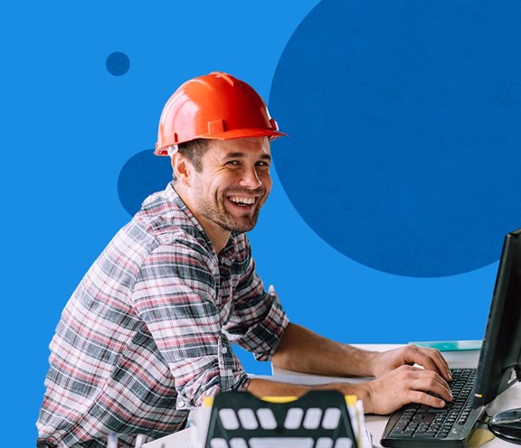 Uomo con caschetto alla scrivania/PC che lavora, sorridente e soddisfatto!